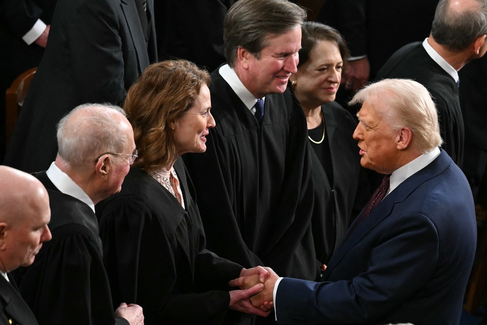 US President Donald Trump (far r.) shakes hands with US Supreme Court Associate Justice Amy Coney Barrett as Trump arrives to address a joint session of Congress in the House Chamber of the US Capitol in Washington, DC, on March 4, 2025.
