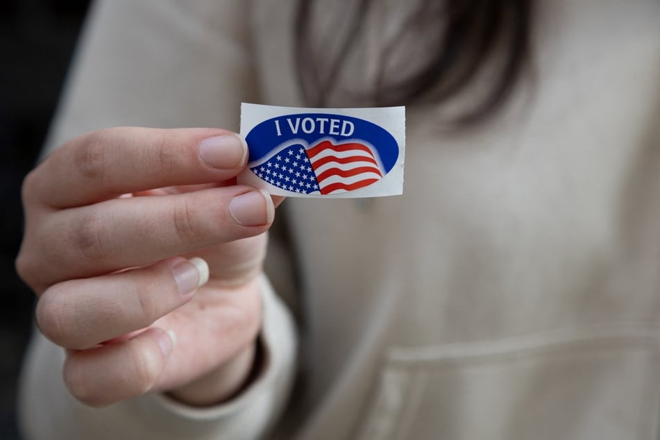 A woman shows off her "I Voted" sticker after dropping off her mail- in ballot in Pittsburgh, Pennsylvania, on the eve of Election Day, November 4, 2024.
