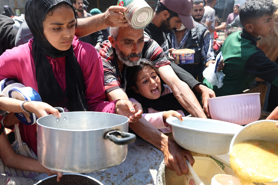 Palestinians line up for a hot meal at a charity kitchen at the Nuseirat refugee camp in the central Gaza Strip on May 4, 2025.