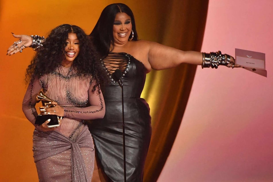 SZA (l.) accepts the Best R&B Song award for Snooze from Lizzo (r.) on stage during the 66th Annual Grammy Awards at the Crypto.com Arena in Los Angeles on February 4, 2024.