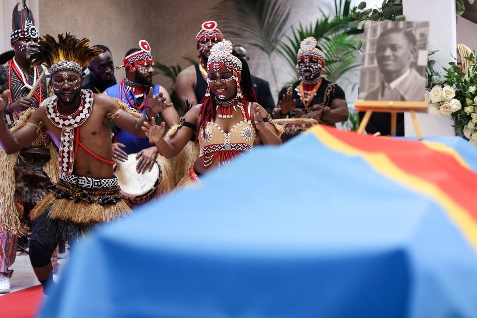 Dancers perform next to the coffin of independence hero Patrice Lumumba during a tribute ceremony at the Congolese Embassy in Brussels before the departure of his last remains on June 21, 2022.