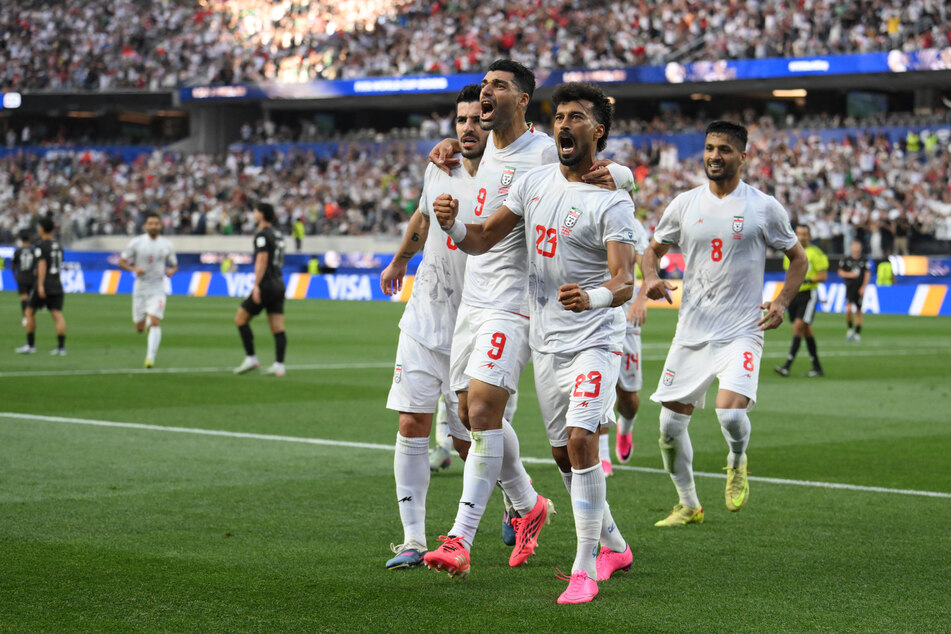Iran's defender Ramin Rezaeian celebrates with teammates after scoring his team's first goal during the World Cup Group G match against New Zealand on June 15, 2026.