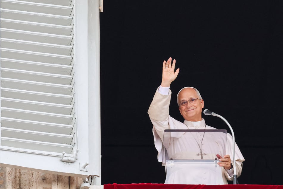 Pope Leo waves as he leads the Angelus prayer from a window of the Apostolic Palace, following his discharge from hospital after surgery for lung cancer, at the Vatican on October 18, 2026.