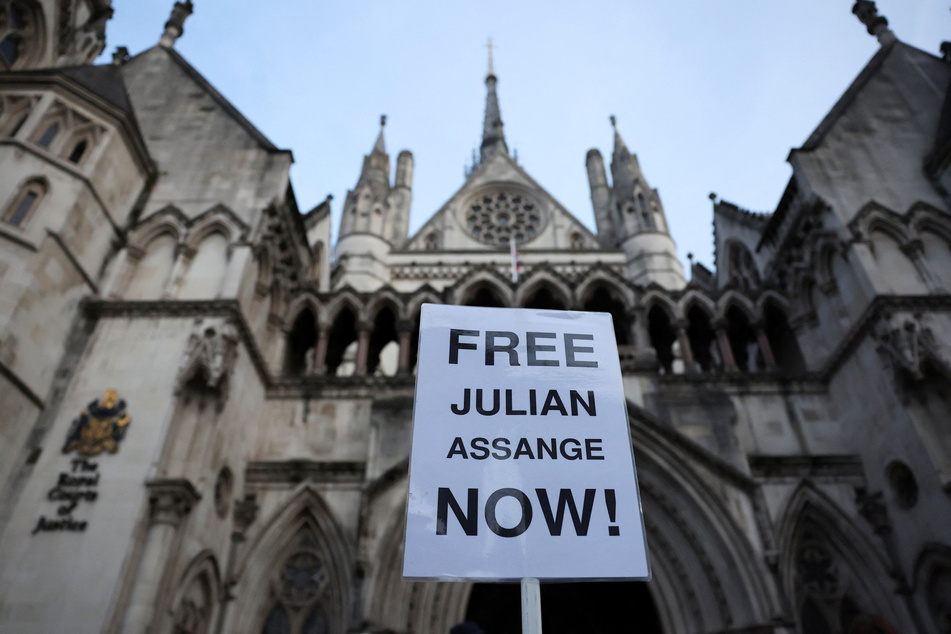Supporters of Julian Assange raise a sign calling for his freedom outside the High Court in London, UK.