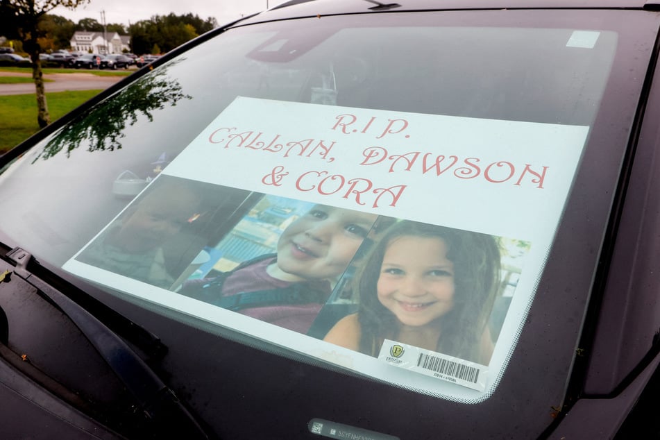 A sign with the images of the three children of Lindsay Clancy in a cart outside the court  on Tuesday. Clancy has claimed she heard a voice ordering her to kill her kids amid a struggle with postpartum psychosis.
