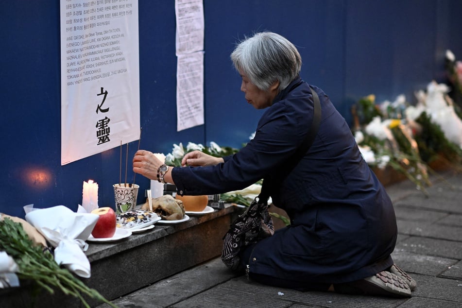 A woman burns incense to pay her respects in an alleyway in Seoul, South Korea, on October 29, 2024, which was the site of the tragic crowd crush that killed 159 people during Halloween celebrations two years prior.