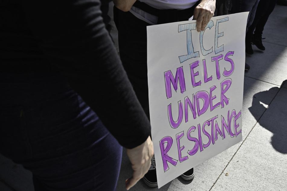 A protestor holds a sign reading "ICE Melts Under Resistance" during a demonstration in Pasadena, California.