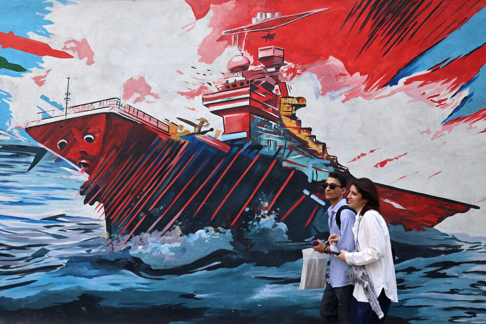 Pedestrians walk past a wall mural along a street in downtown of Tehran on August 31, 2026. Control over the Strait of Hormuz remains a key point of contention in the US-Iran war.