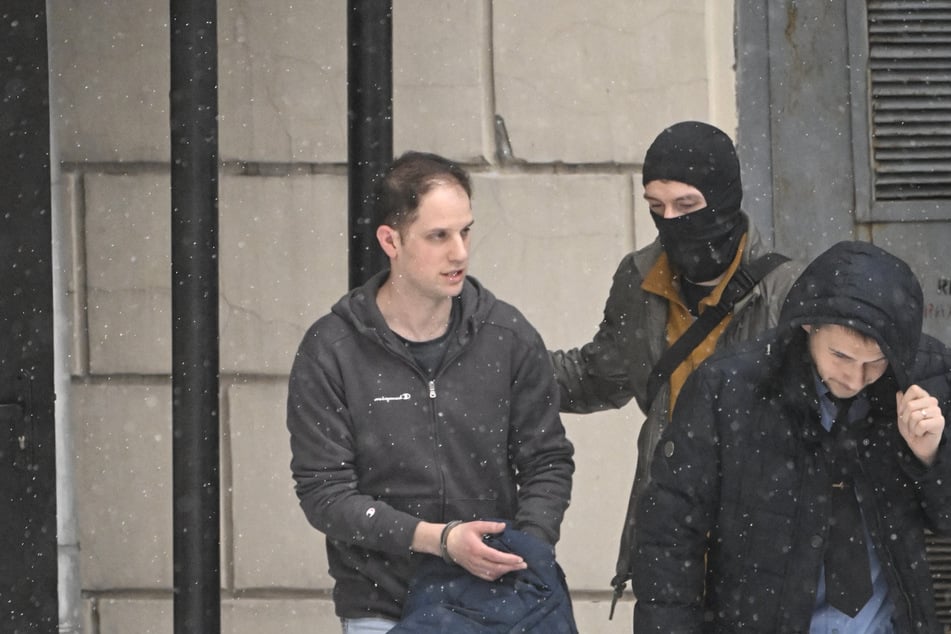 Detained Wall Street Journal writer Evan Gershkovich (l.) is escorted out of the Lefortovsky Court building in Moscow on Friday after his espionage trial was extended until March 30.