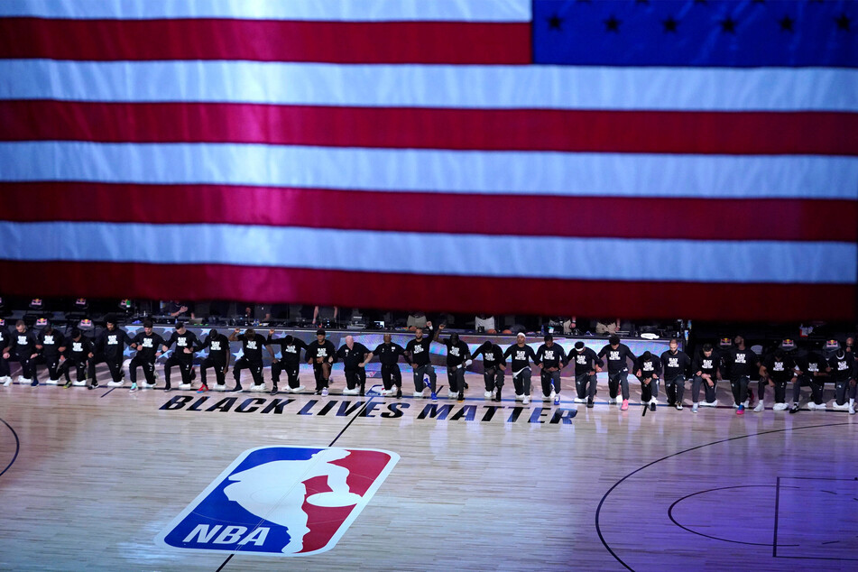 Members of the Orlando Magic and Brooklyn Nets kneel around a Black Lives Matter sign during an NBA basketball game in 2020.