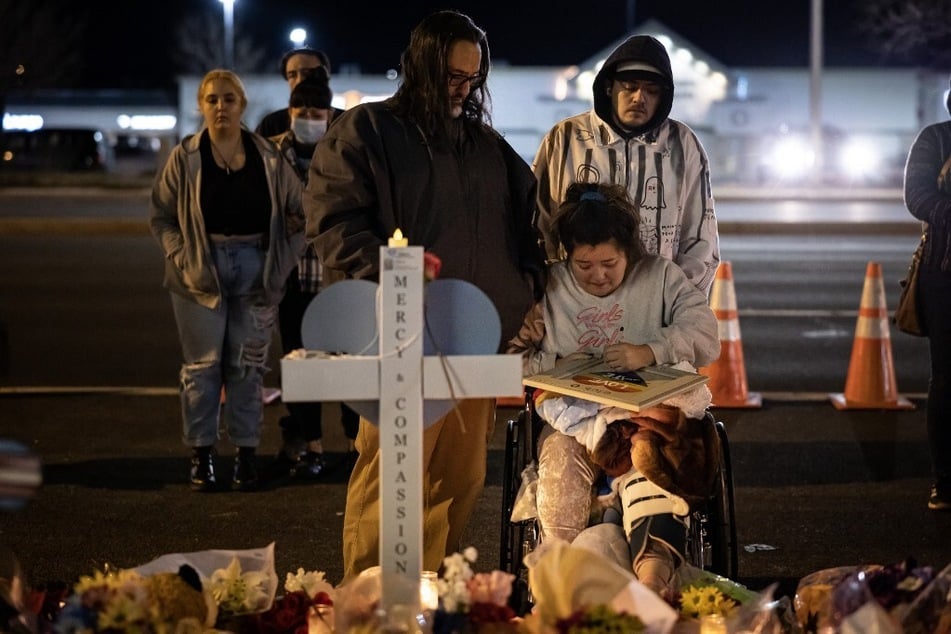 Richard Fierro consoles his daughter, Kassandra, as she signs a plaque to her slain boyfriend at a memorial outside of Club Q.
