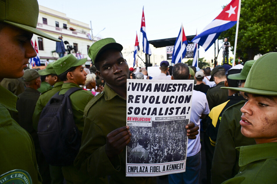 A man holds a poster reading "Long live our socialist revolution" during celebrations marking the 65th anniversary of the declaration of the socialist character of the Cuban Revolution in Havana on April 16, 2026.