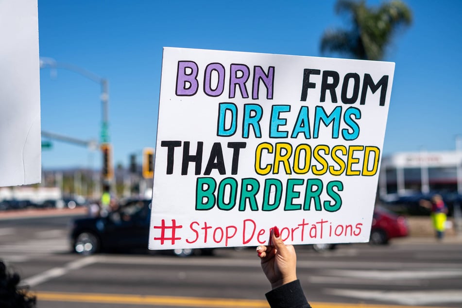A demonstrator holds a sign protesting the Trump administration's mass deportations in Escondido, California.