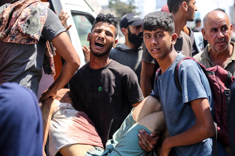 Palestinians mourn as they carry a youth who was shot while seeking aid at a Gaza Humanitarian Foundation distribution point, at the entrance of the Bureij refugee camp in the central Gaza Strip on July 27, 2025.
