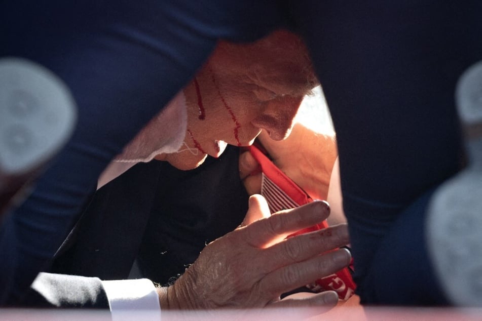 President Donald Trump lies on the ground bleeding after being shot in the ear during a rally on July 13, 2024 in Butler, Pennsylvania.