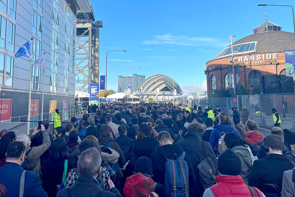 Cop26 delegates wait in a long queue for entrance to the summit at the Scottish Exhibition Centre in Glasgow.