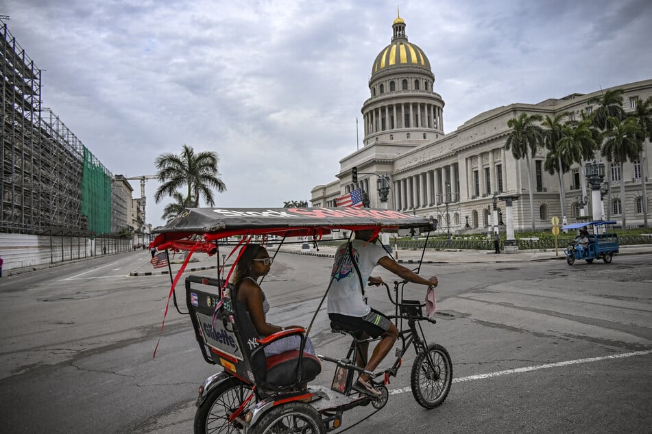 A bicycle taxi decorated with a US flag passes in front of the Havana Capitol on July 11, 2026.