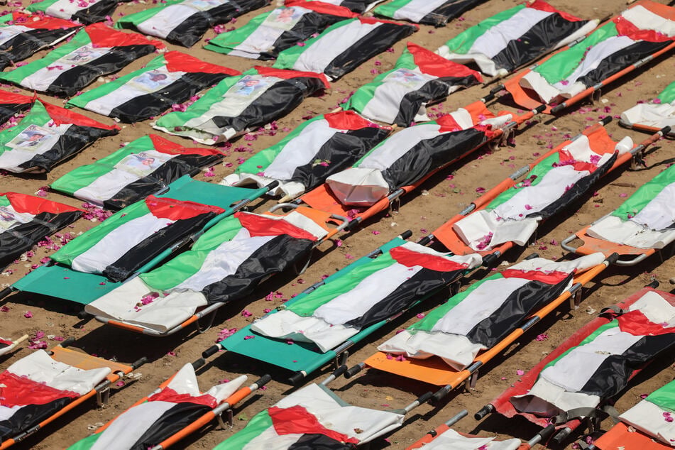 The flag-covered remains of members of the Abu Sharia and al-Hasayna families, recently recovered from the rubble of residential buildings in the al-Sabra neighborhood which were struck by Israeli bombardments in November 2023, are pictured during a mass funeral in Gaza City on August 4, 2026.