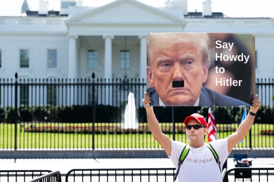 A protester holds a sign depicting US President Donald Trump as Adolf Hitler outside the White House on October 3, 2025.