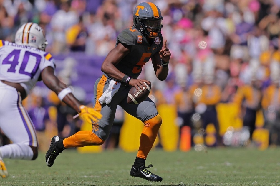 Hendon Hooker of the Tennessee Volunteers runs with the ball as Harold Perkins Jr. of the LSU Tigers defends during the first half of a game at Tiger Stadium.