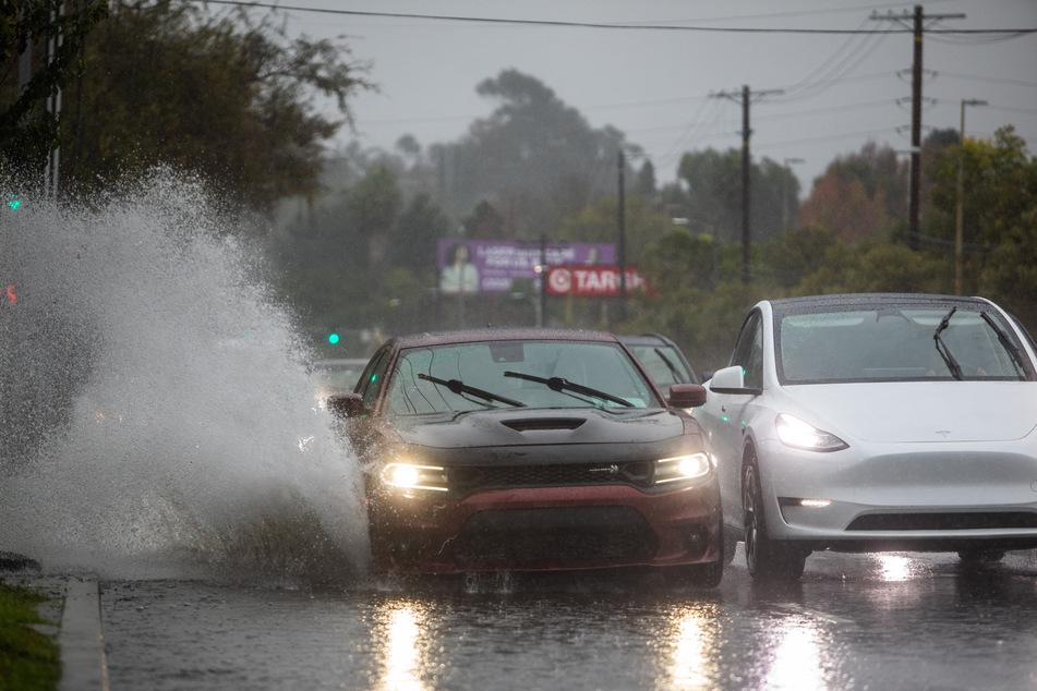 A car drives through a flooded road on La Cienega Boulevard on Wednesday in Los Angeles, California.