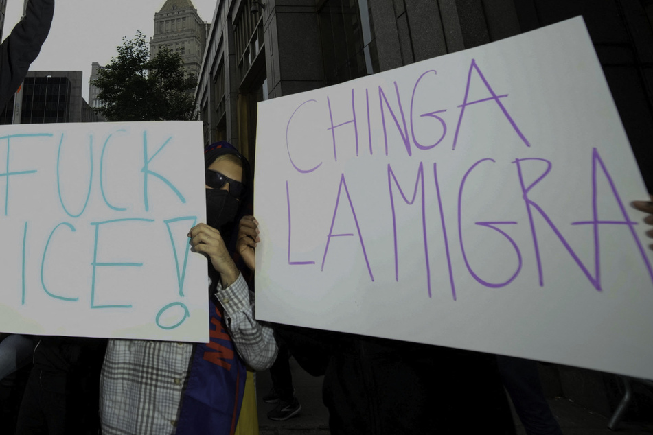 New Yorkers raise protest signs reading "F*ck ICE!" and "Chinga la migra" in opposition to the Trump administration's mass deportation agenda.