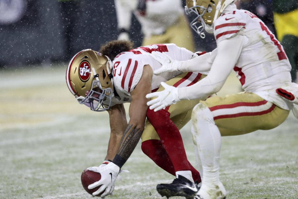 Talanoa Hufanga (l.) of the 49ers picks up a blocked punt and returns it for a touchdown against the Packers.