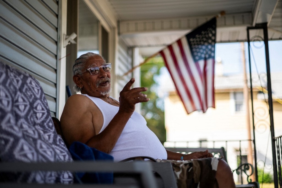 Vietnam War veteran William Thompson sits on the porch of the house where he lives near a Haitian Community Help and Support Center.