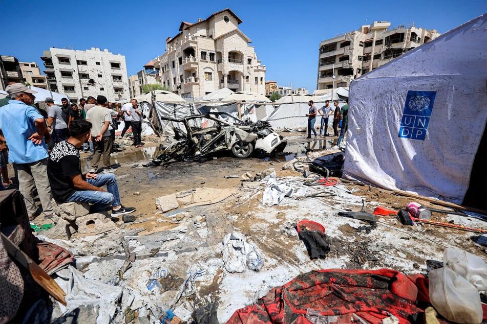 People gather near a destroyed vehicle following an Israeli strike in the Rimal neighborhood of Gaza City on September 1, 2026.