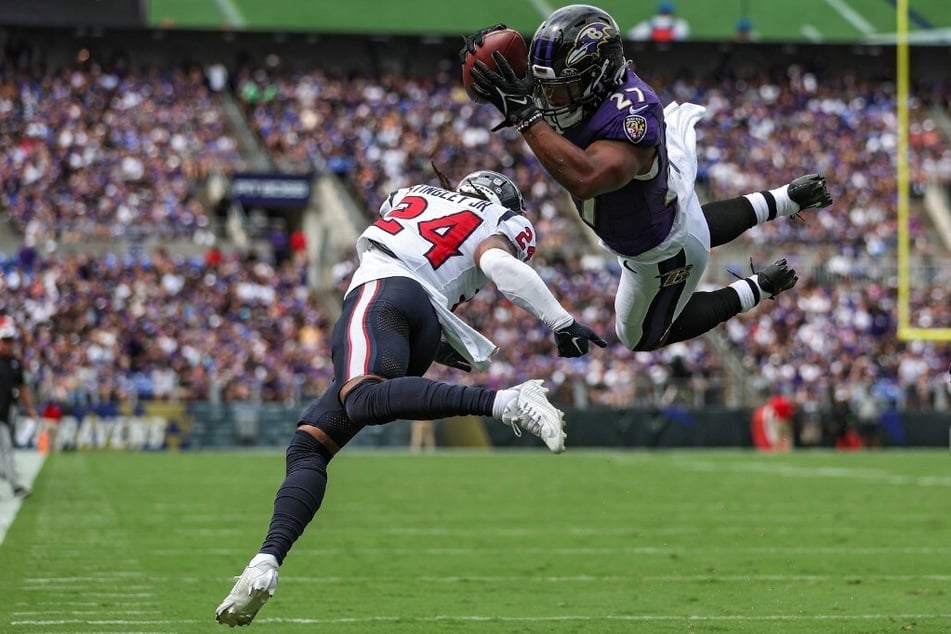 J.K. Dobbins of the Baltimore Ravens dives into the end zone past Derek Stingley Jr. of the Houston Texans for a touchdown in the first quarter at M&T Bank Stadium.