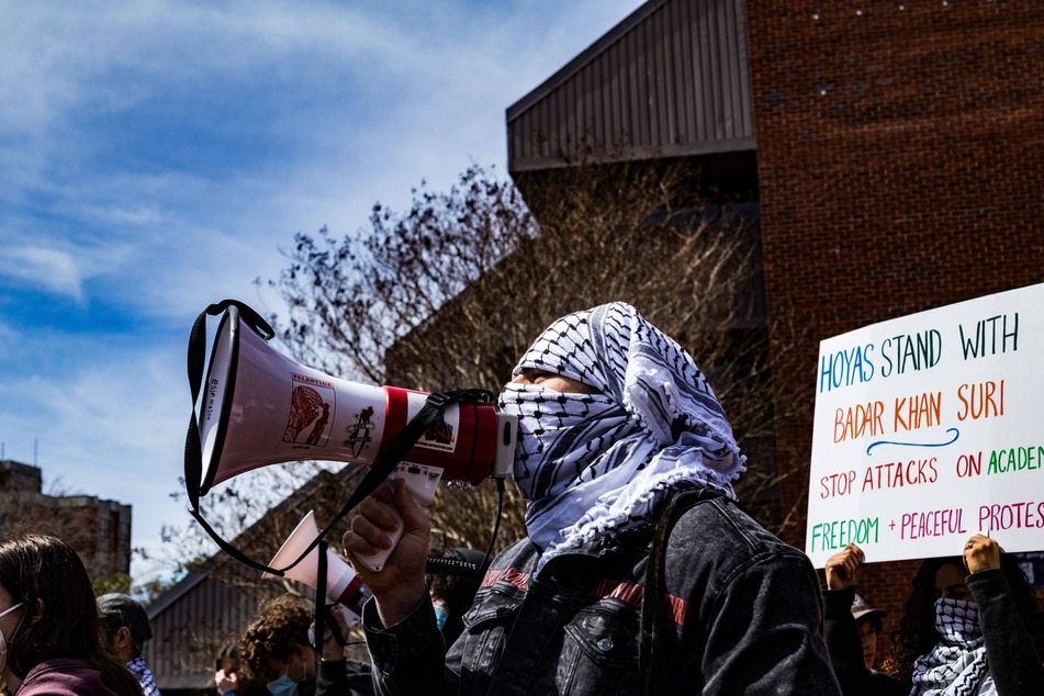 A protester raises a sign reading "Hoyas Stand with Badar Khan Suri" during a rally on the Georgetown University campus calling for the detained academic's release.