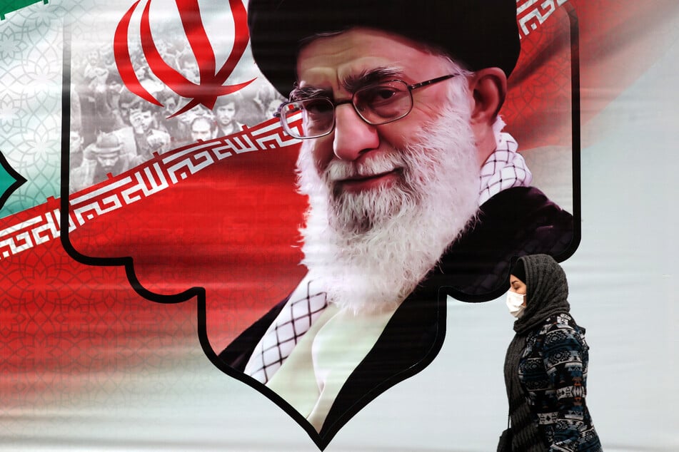 An Iranian woman walks past a billboard showing Iran's Supreme Leader Ayatollah Ali Khamenei in the capital Tehran. Khamenei accused arch-foes the United States and Israel of fueling the wave of nationwide unrest sparked by outrage over the death of Mahsa Amini.