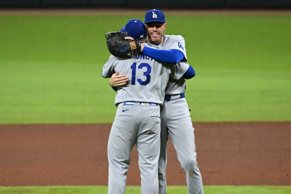 Max Muncy #13 and Freddie Freeman #5 of the Los Angeles Dodgers embrace after winning Game 4 of the National League Division Series at Truist Park on Wednesday. The defending World Series champions are now heading to the NLCS.
