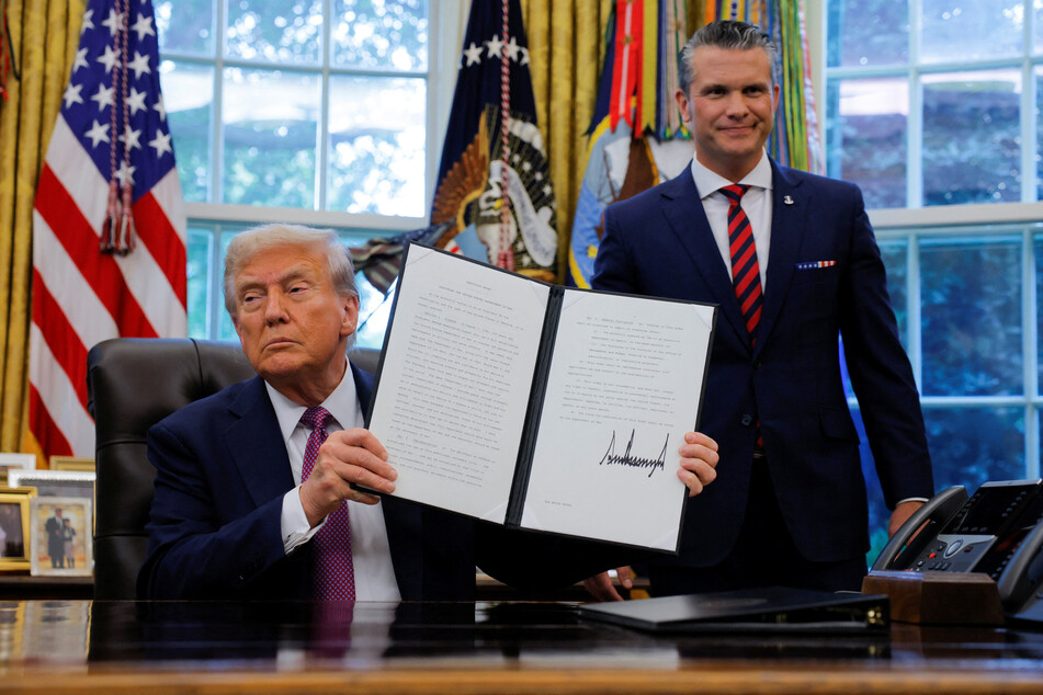 President Donald Trump (l.), accompanied by Defense Secretary Pete Hegseth, shows a signed executive order to rename the Department of Defense the "Department of War," in the Oval Office of the White House on September 5, 2025.