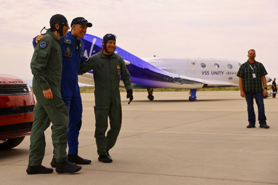 Crew members hug each other after their return from Virgin Galactic's first commercial flight to the edge of space.