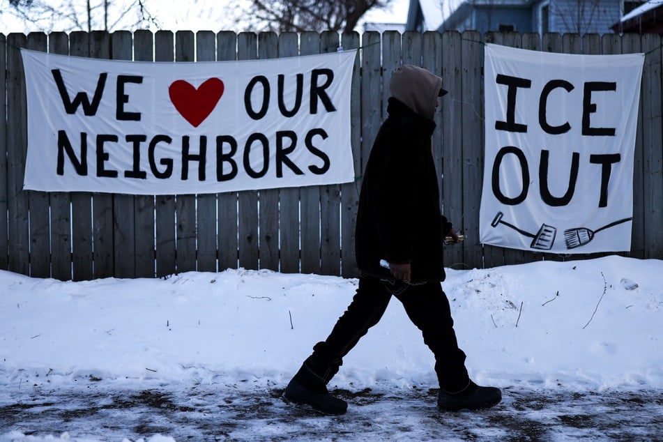 A man walks past signs reading "ICE Out" hanging on a fence in Minneapolis, Minnesota, on February 3, 2026.