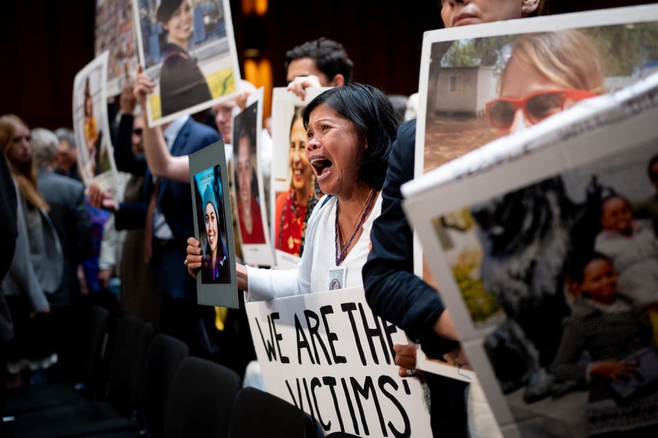 Clariss Moore (c.) holds a photograph of her daughter Danielle Moore and stands with other family members of those killed in the Ethiopian Airlines Flight 302 and Lion Air Flight 610 during Tuesday's Senate hearing.
