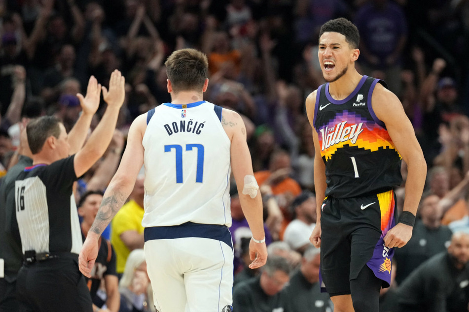 The Mavs' Luka Dončić walks away as the Suns shooting guard Devin Booker celebrates.