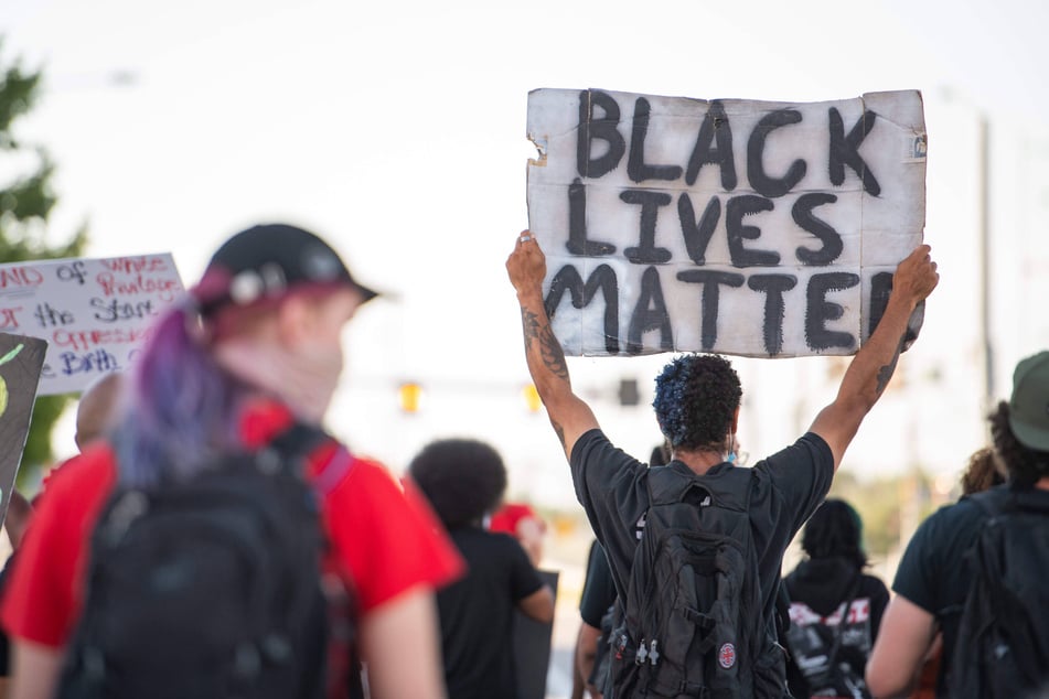 Hundreds of people occupy the space around the Aurora Police Station to protest the killing of Elijah McClain.