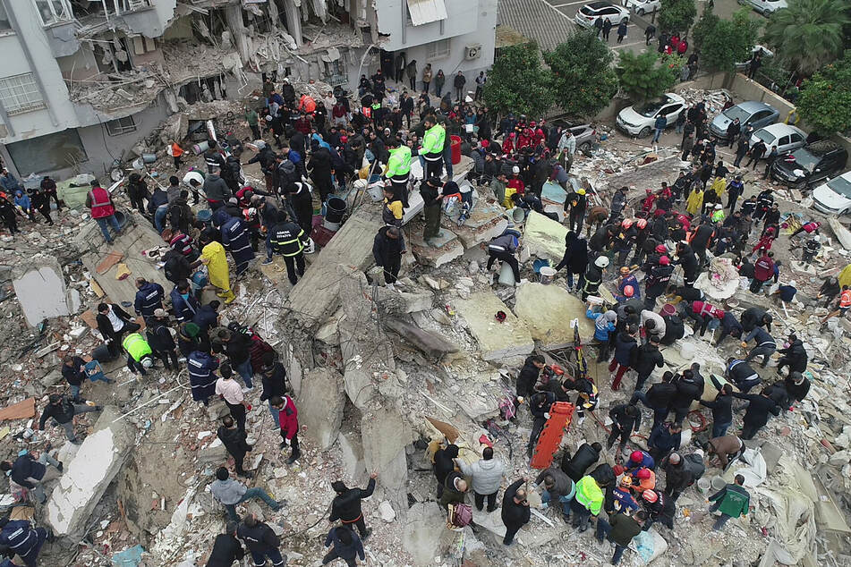 Following a devastating earthquake, people search for survivors among the rubble of a building in Adana, Turkey.