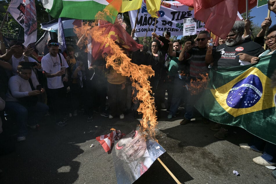 Demonstrators burn a US flag and a picture of US President Donald Trump during a protest in defence of national sovereignty following the US government's trade taxes and sanctions on Brazil, near the US consulate, in Sao Paulo, Brazil, on August 1, 2025.