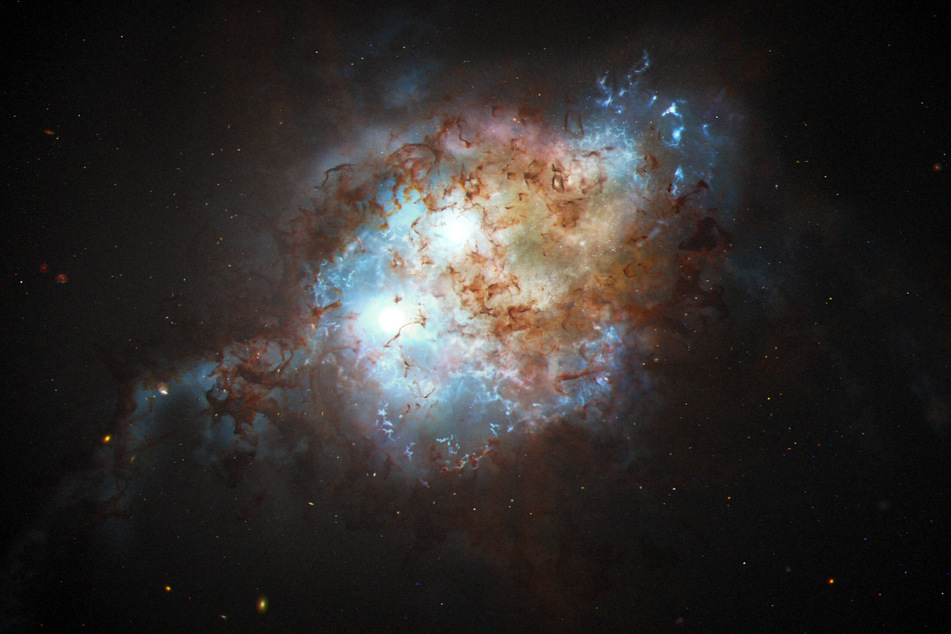 An artist's depiction shows the brilliant glare of two quasars residing in the cores of two galaxies that are in the chaotic process of merging.