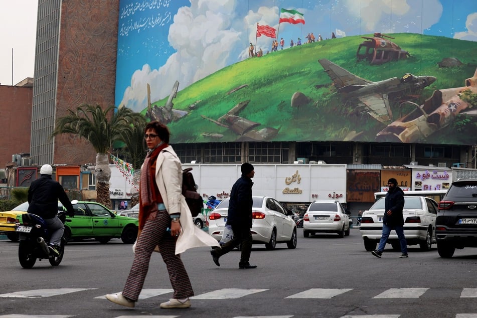 An Iranian woman walks past a huge anti-US billboard displayed on a building in Tehran's Valiasr Square on Sunday.