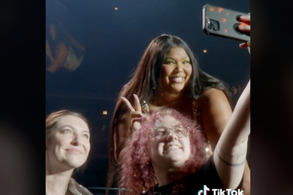 Lizzo posed with fans who brought the huge posters of her boo Myke Wright's face to her concert.