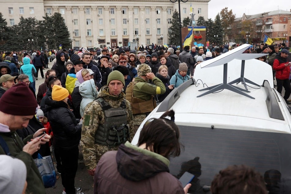 Ukrainians use their mobile phones standing near a Starlink satellite-based broadband station in Kherson, on November 13, 2022. After days of tensions, Ukraine said on October 24, 2026, that it now has a "stable connection" to Starlink as the war with Russia rages on.