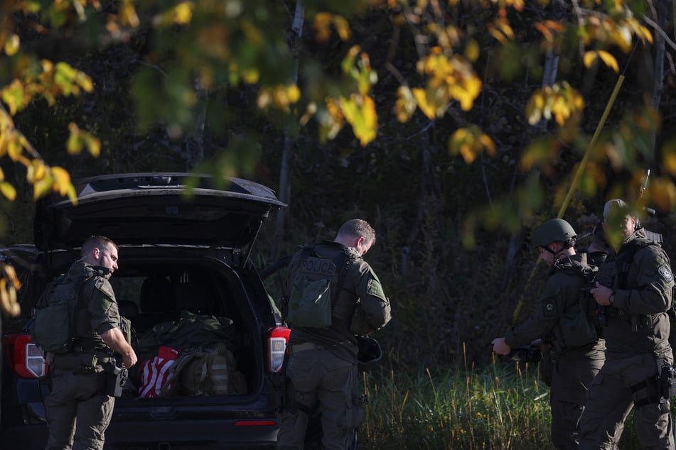 Law enforcement officers gather at Lewiston High School as the search for the suspect in the deadly Maine mass shootings continues.