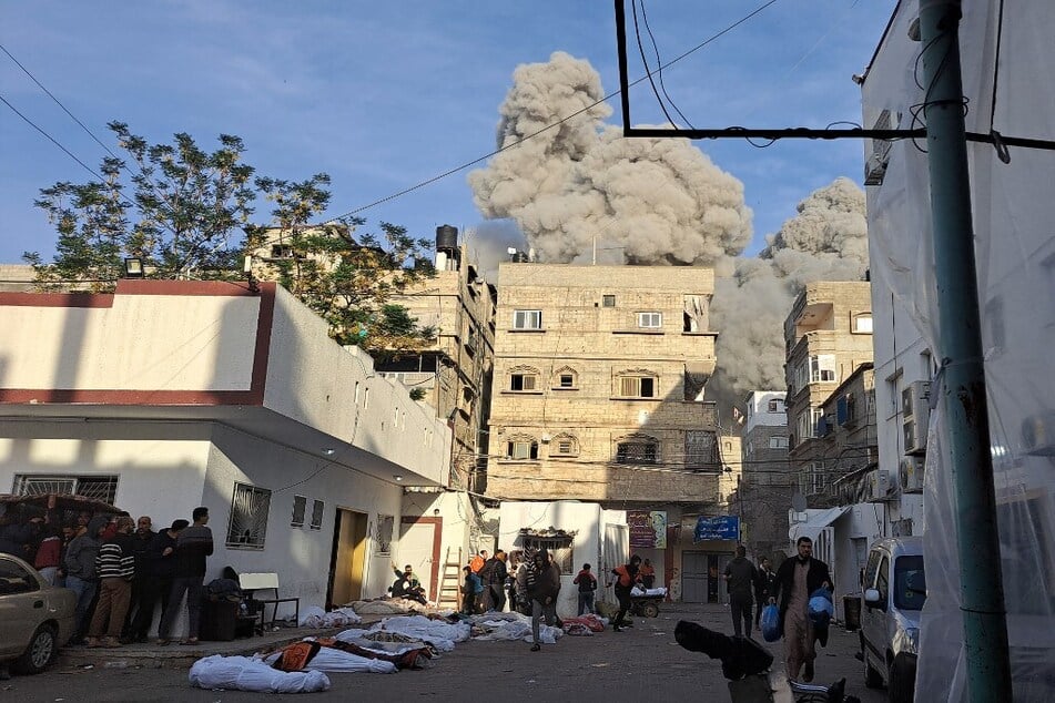 Palestinians run for cover next to covered bodies after an Israeli airstrike near the Kamal Adwan hospital in Beit Lahia in the northern Gaza Strip.