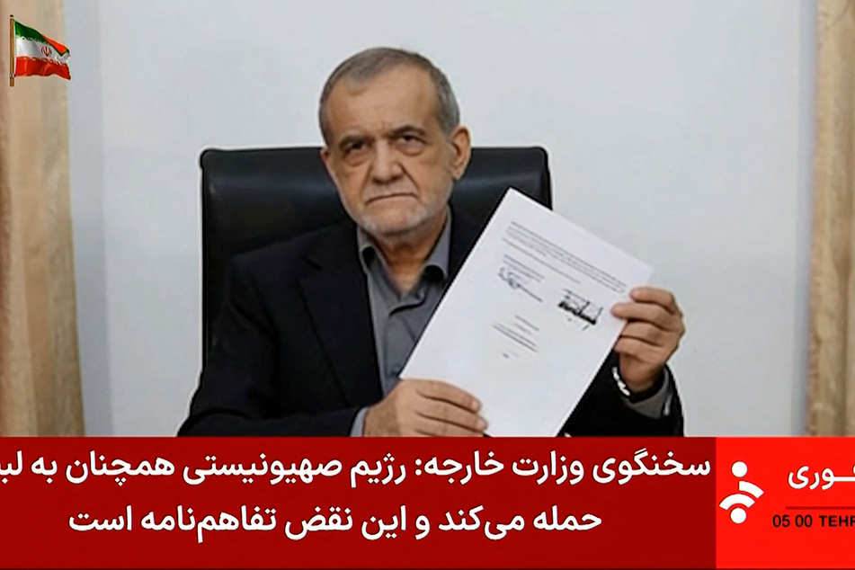Iran's President Masoud Pezeshkian holds a document showing a memorandum of understanding he signed to end the Middle East war.