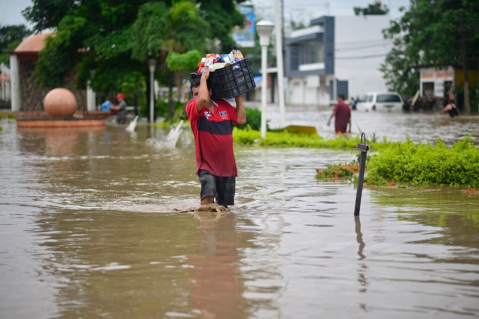 A man wades through a flooded street after heavy rains in Poza Rica, Veracruz state, Mexico, on October 10, 2025.