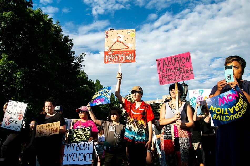 Abortion rights protesters hold signs reading "Make Abortion Safe and Legal" and "Never Again" in a June 2022 rally in Iowa City following the Supreme Court's decision to overturn Roe v. Wade protections.
